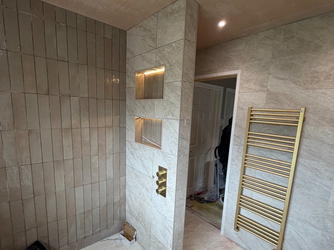 Bathroom lighting - finished shower wall with LED-lit niches, ceiling spotlights and a brass towel rail