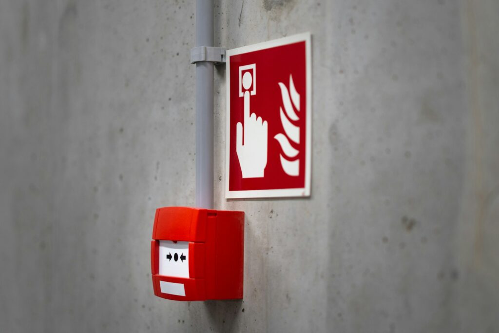 Fire alarm categories: red manual call point with fire alarm sign on a commercial building wall