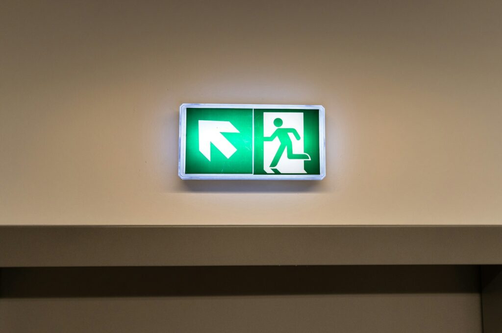 How often should emergency lights be tested: illuminated green fire exit sign above an escape route