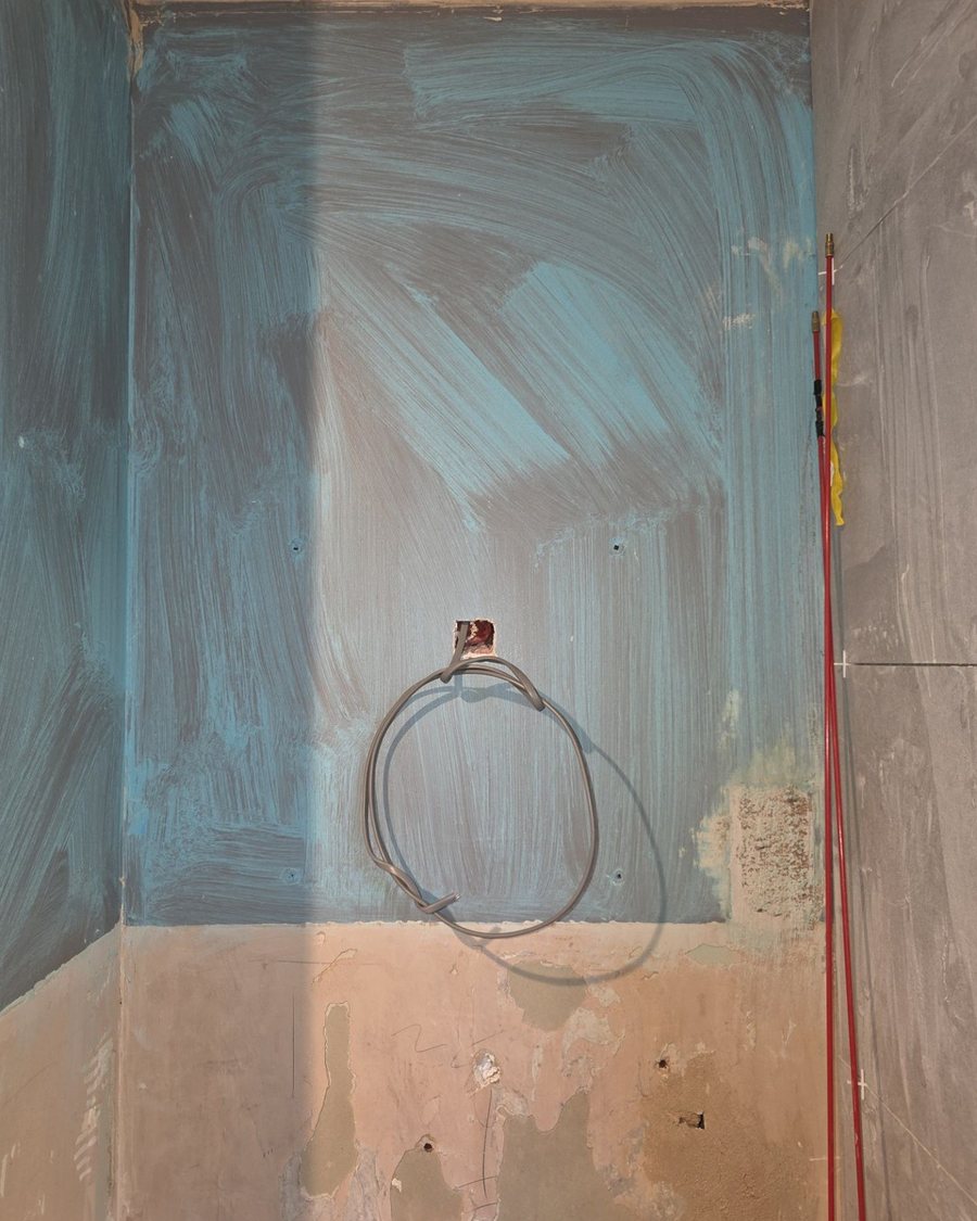 Supply for an illuminated mirror left coiled out of the wall board before tiling